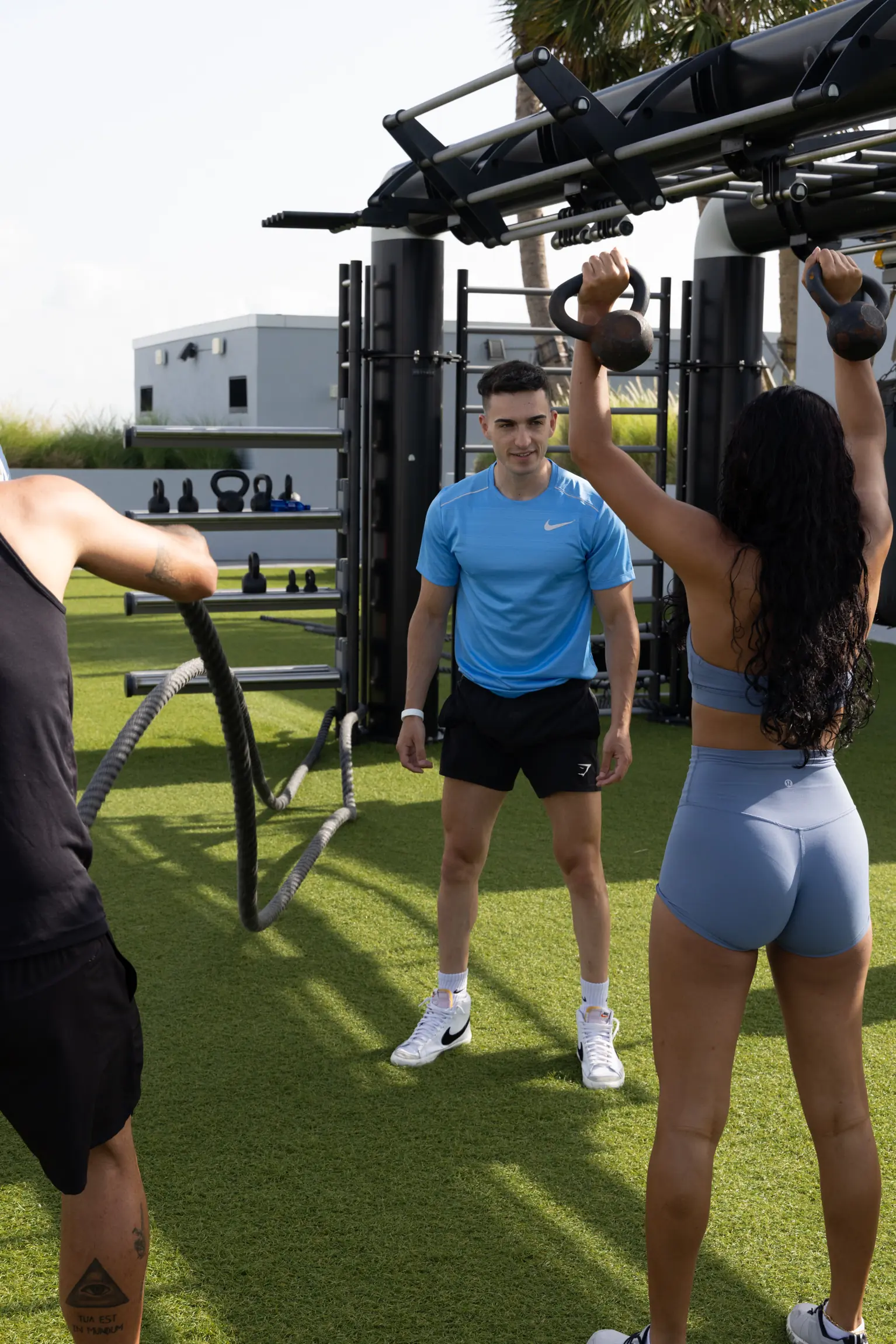 Entrenador supervisando un entrenamiento con pesas rusas en un gimnasio de azotea en Miami